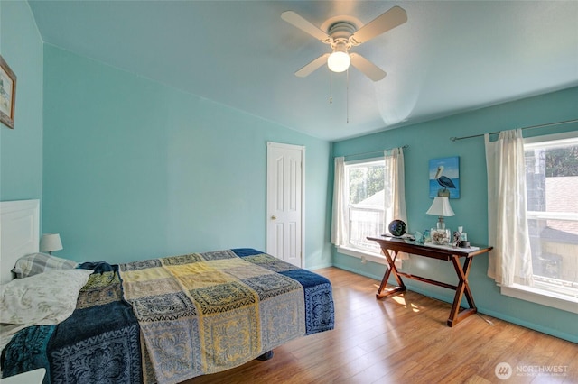 bedroom featuring a ceiling fan, multiple windows, vaulted ceiling, and wood finished floors