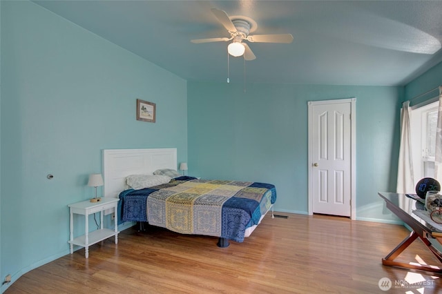 bedroom featuring ceiling fan, wood finished floors, visible vents, and baseboards