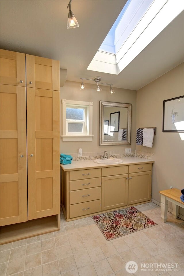 bathroom featuring lofted ceiling with skylight, vanity, and tile patterned floors