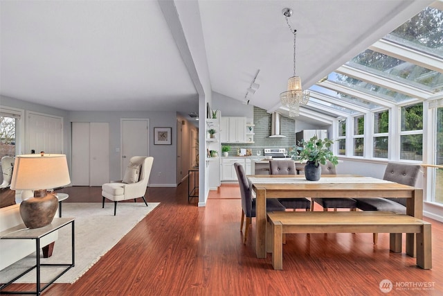 dining area with lofted ceiling, a notable chandelier, and wood-type flooring