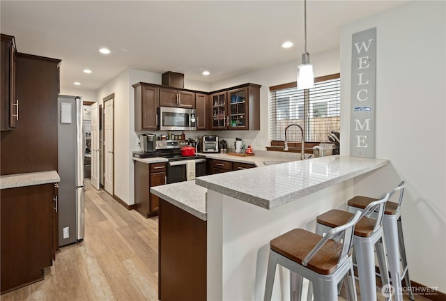 kitchen with sink, decorative light fixtures, stainless steel appliances, kitchen peninsula, and a breakfast bar area