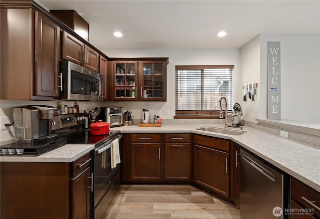 kitchen with light wood-type flooring, appliances with stainless steel finishes, sink, and dark brown cabinets