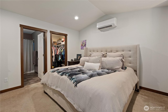 carpeted bedroom featuring lofted ceiling, a wall mounted air conditioner, ensuite bath, a closet, and a spacious closet