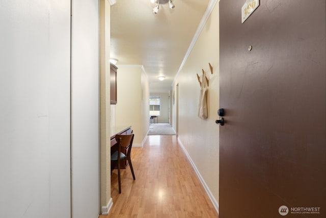 hall with ornamental molding, light wood-style flooring, and baseboards