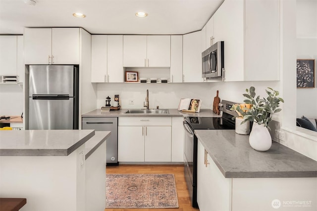 kitchen featuring stainless steel appliances, recessed lighting, white cabinetry, and a sink