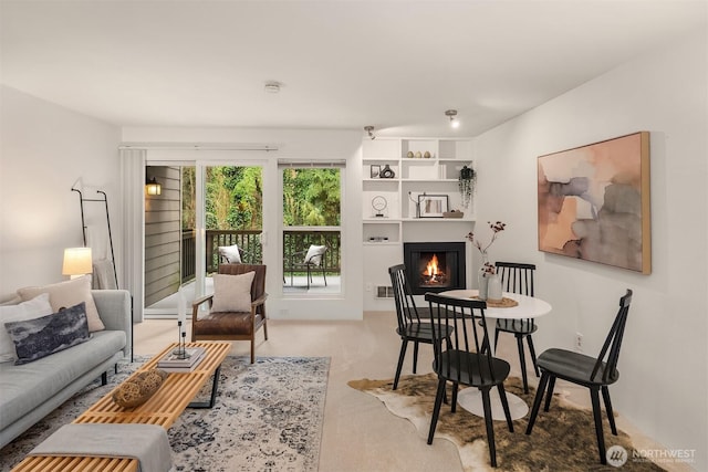 living area featuring a warm lit fireplace and carpet