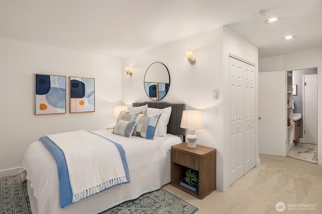 bedroom featuring light carpet, a closet, ensuite bath, and recessed lighting