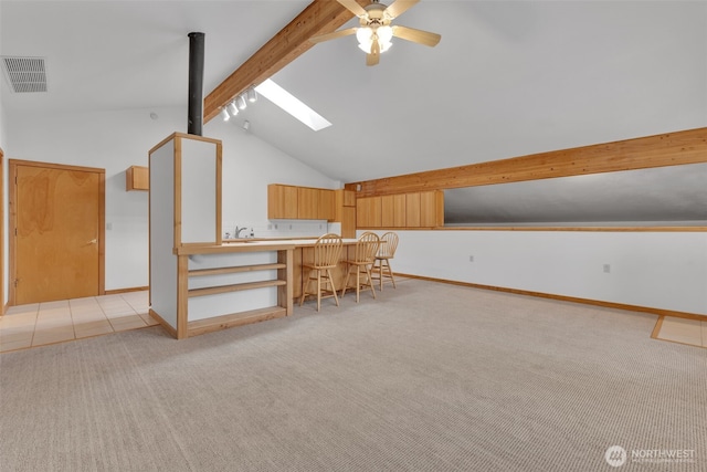 additional living space with visible vents, baseboards, lofted ceiling with skylight, light colored carpet, and a ceiling fan