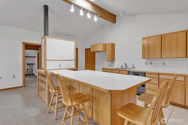 kitchen with a breakfast bar, lofted ceiling with beams, decorative backsplash, light countertops, and dishwasher