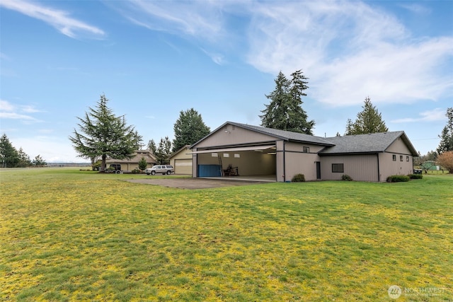 rear view of property with a yard, a garage, and driveway