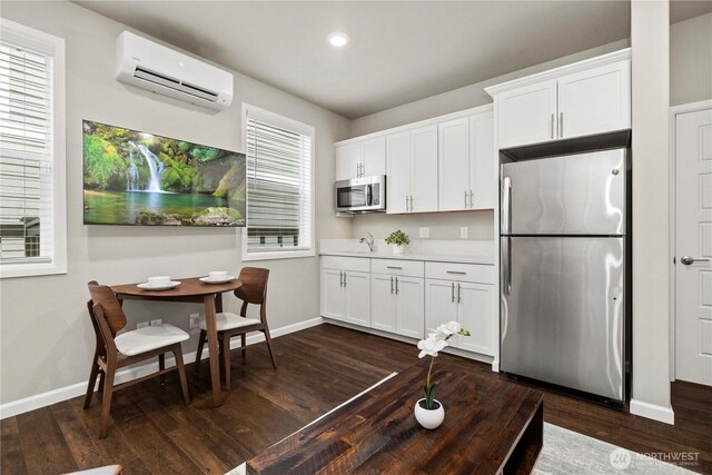 kitchen featuring stainless steel appliances, dark wood-style flooring, white cabinets, light countertops, and a wall mounted air conditioner