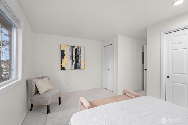 bedroom with recessed lighting, light colored carpet, baseboards, and two closets