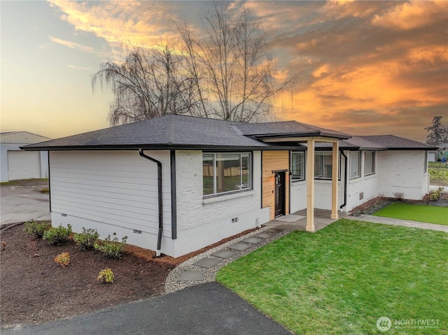 view of front of property with a yard, brick siding, crawl space, and roof with shingles