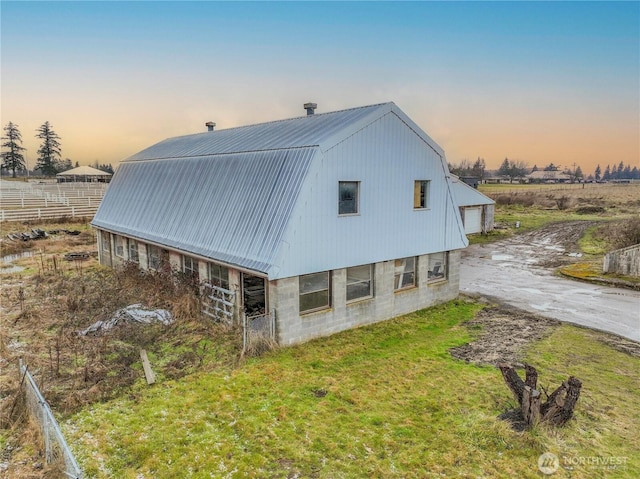 view of home's exterior featuring metal roof, a garage, an outdoor structure, a gambrel roof, and driveway