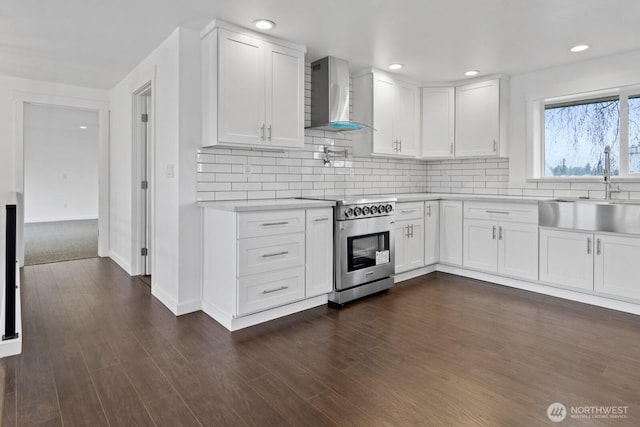 kitchen with light countertops, decorative backsplash, a sink, high end range, and wall chimney exhaust hood