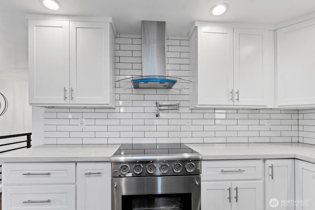 kitchen with white cabinets, wall chimney exhaust hood, stainless steel range, and light countertops