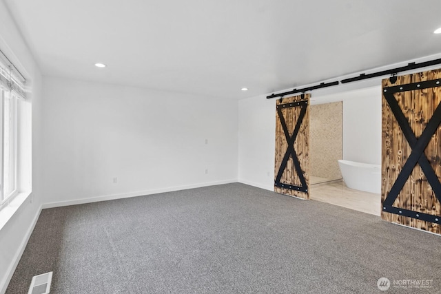 unfurnished living room with carpet floors, recessed lighting, visible vents, and a barn door