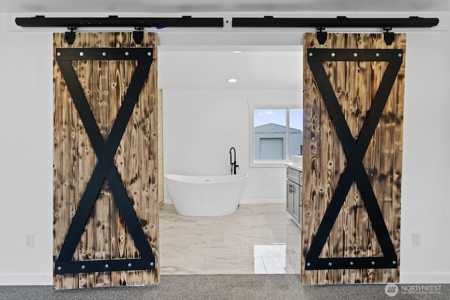 full bath with marble finish floor, recessed lighting, a freestanding tub, and baseboards