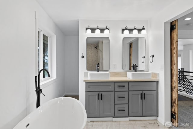 bathroom featuring double vanity, a freestanding tub, and a sink