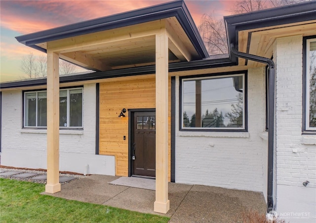 exterior entry at dusk featuring brick siding