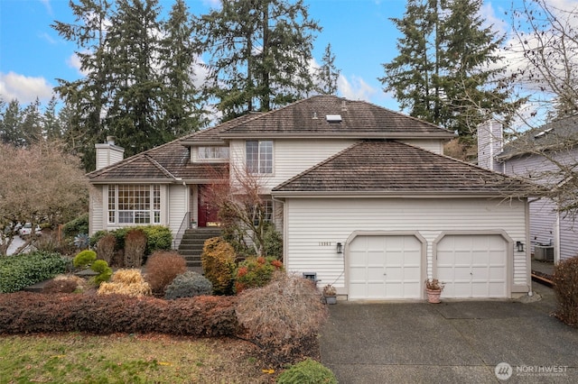 traditional home with driveway, a chimney, and an attached garage