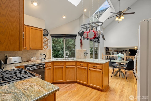 kitchen with a peninsula, a skylight, a sink, black dishwasher, and freestanding refrigerator