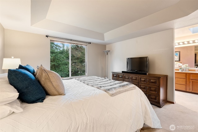 bedroom featuring ensuite bathroom, baseboards, a raised ceiling, and light colored carpet