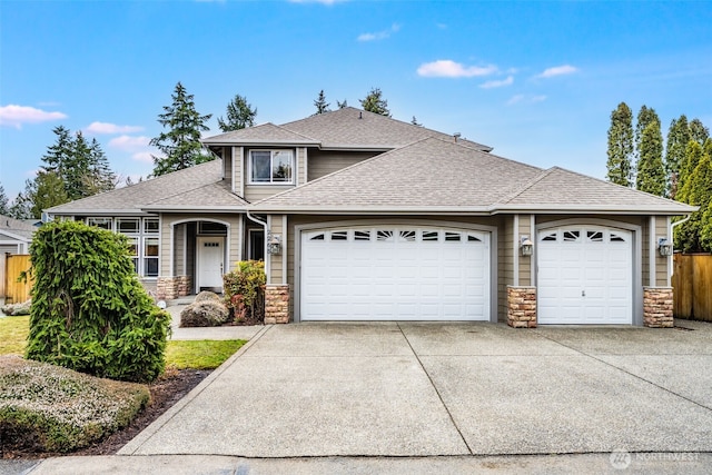 view of front of home featuring a garage, stone siding, roof with shingles, and concrete driveway