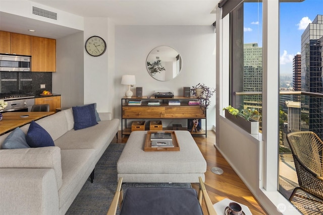 living area featuring a view of city, wood finished floors, visible vents, and baseboards