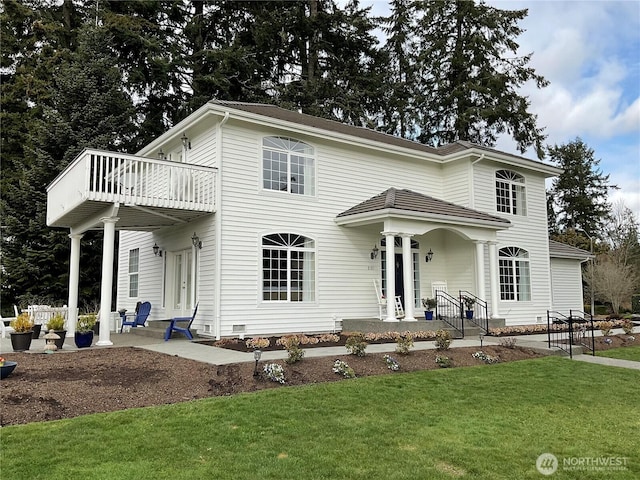 view of front of house with a front yard, a patio, and a balcony