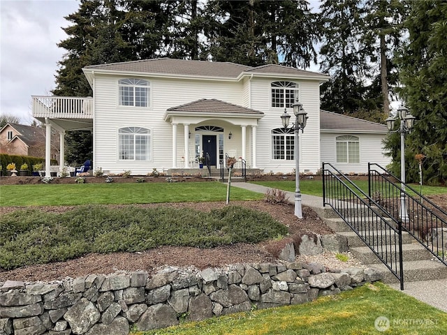 view of front of property with a balcony and a front lawn