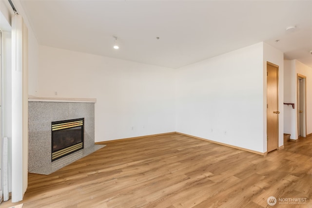 unfurnished living room featuring light wood-style flooring, a fireplace, and baseboards