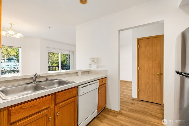 kitchen featuring a sink, brown cabinetry, light countertops, and dishwasher