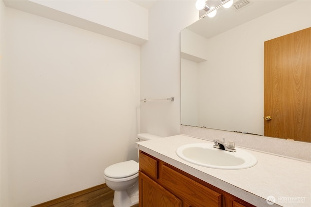 half bathroom featuring toilet, vanity, and visible vents