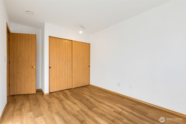 unfurnished bedroom with light wood-style floors and a closet