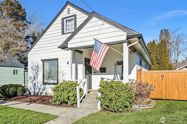 bungalow featuring a front lawn and fence