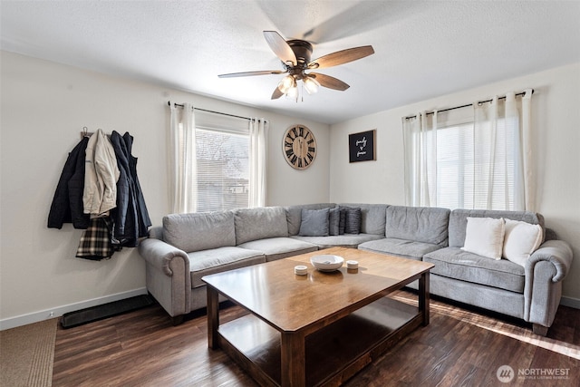 living area featuring a textured ceiling, dark wood finished floors, a ceiling fan, and baseboards