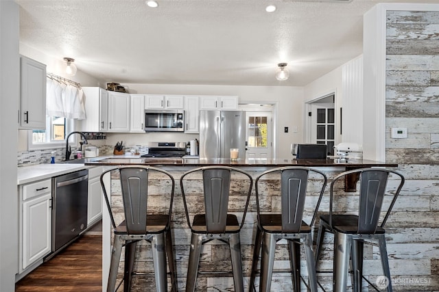 kitchen featuring appliances with stainless steel finishes, white cabinets, a sink, and a breakfast bar area