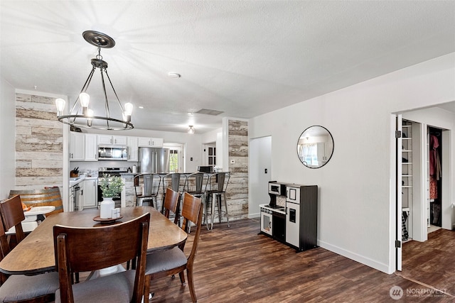 dining area with a textured ceiling, visible vents, baseboards, dark wood-style floors, and an inviting chandelier