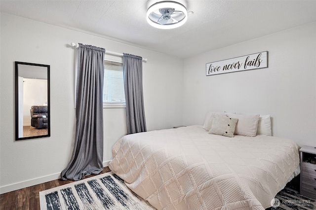 bedroom featuring a textured ceiling, dark wood-type flooring, and baseboards