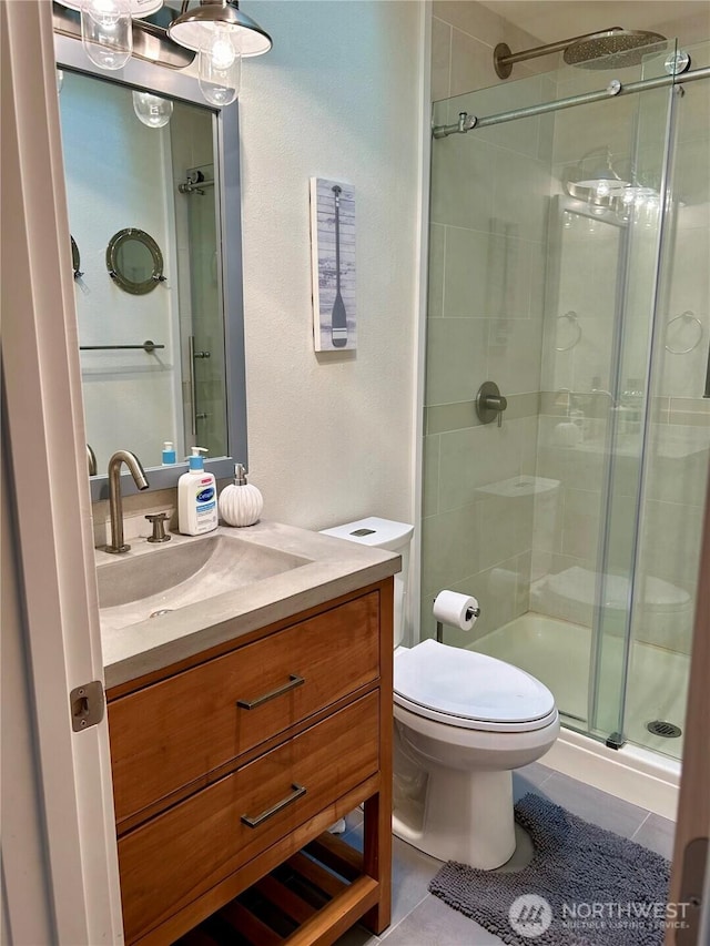 bathroom with vanity, toilet, tile patterned floors, and walk in shower