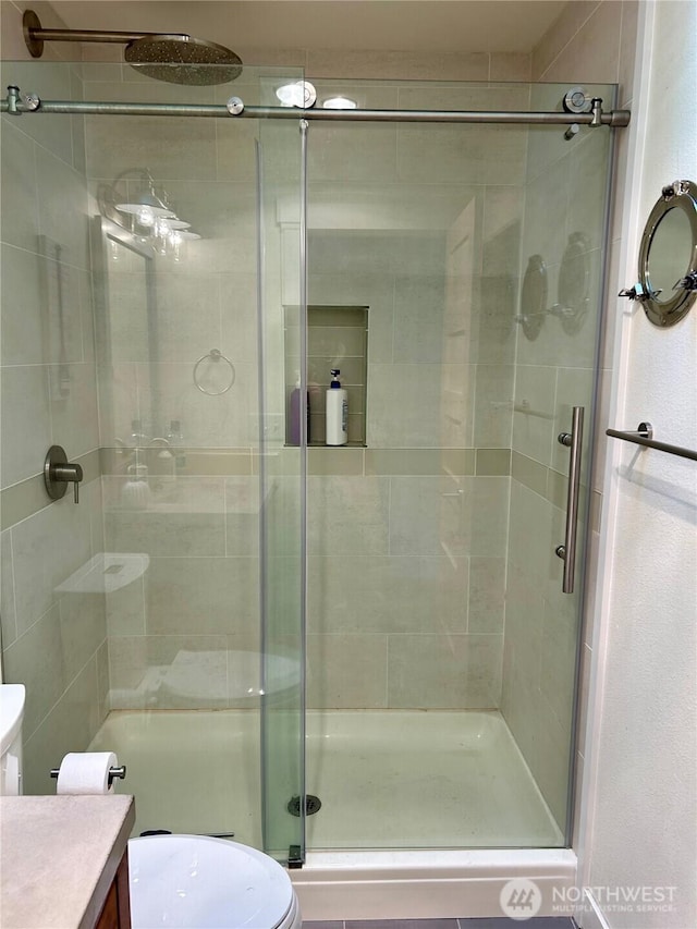 bathroom with toilet, a shower with shower door, and vanity