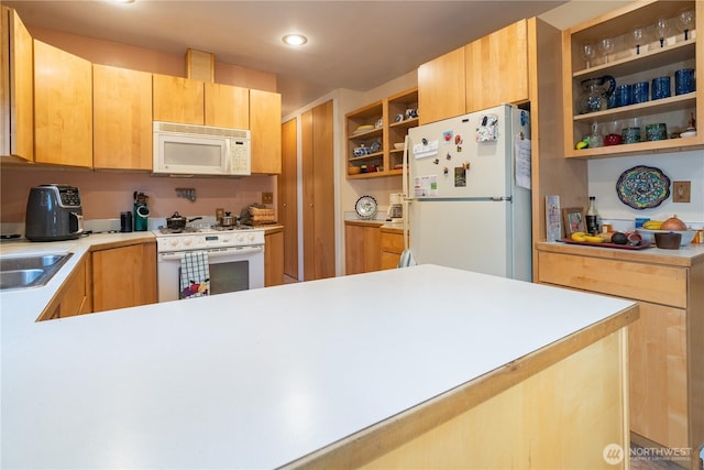 kitchen featuring white appliances, light countertops, a sink, and a peninsula