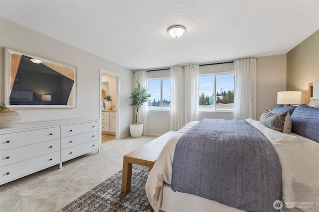 bedroom with a textured ceiling, ensuite bath, and light colored carpet