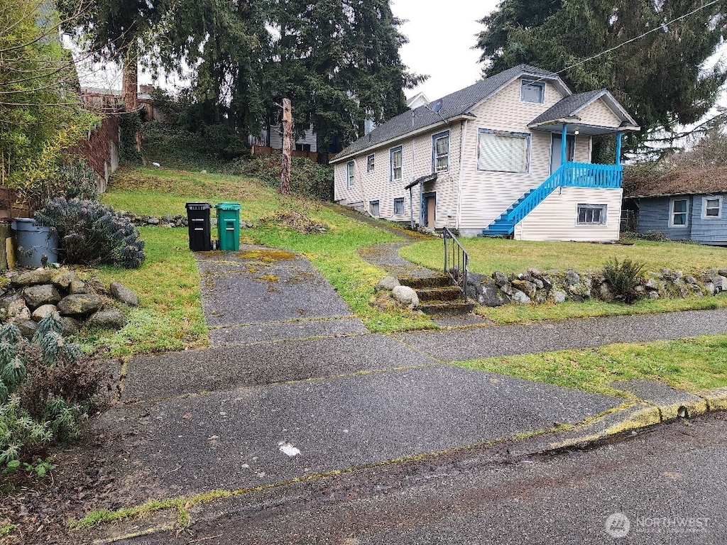 view of property exterior with a yard and stairway