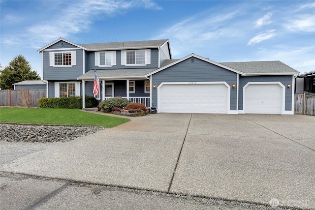 traditional-style home with a porch, an attached garage, fence, driveway, and a front yard