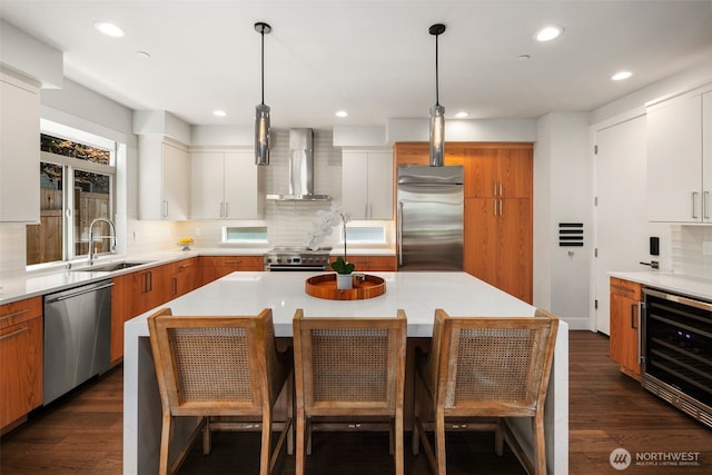 kitchen with a kitchen island, white cabinetry, light countertops, wall chimney exhaust hood, and high end appliances