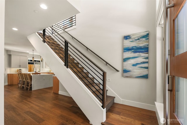 stairway with recessed lighting, baseboards, and wood finished floors