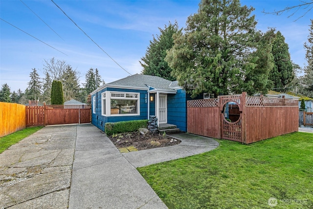 view of front facade with driveway, a front lawn, a fenced front yard, and a gate