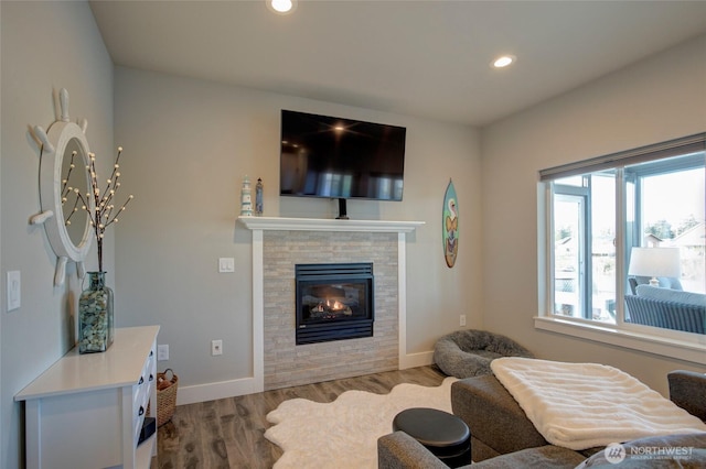 living room featuring baseboards, wood finished floors, a glass covered fireplace, and recessed lighting